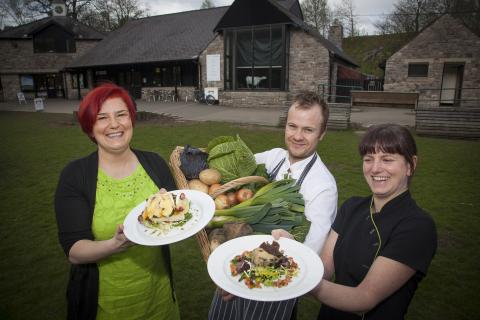 Chef holding vegetables and women holding cooked food outside cafe