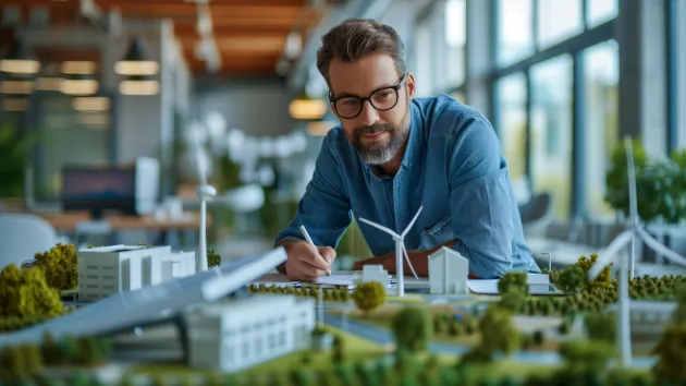 Designer, engineer looking at a scaled model of green space, wind turbines