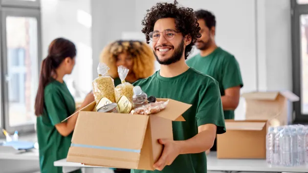 Group of volunteers carrying boxes of food