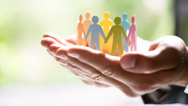 hand holding paper silhouettes of people