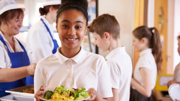 schoolgirl holding a plate of food in canteen