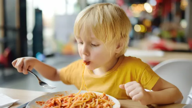 Child eating pasta at a restaurant