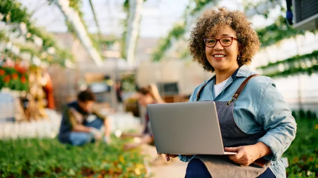 person working at a garden centre looking at a laptop 