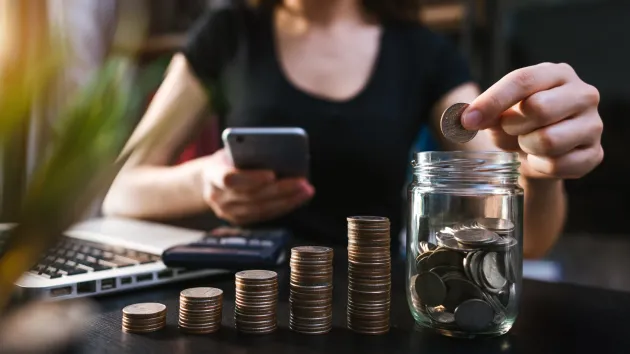 person counting coins and putting them in jars - budgeting
