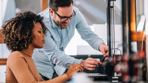 Colleagues using a 3D printer