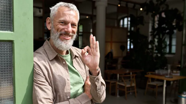 happy business owner stood outside premises 