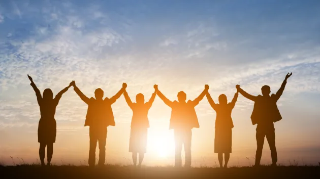 group of employees holding their hands up in celebration 