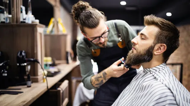 Barber trimming a client's beard 