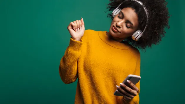 person wearing a yellow sweater, listening to music through headphones 