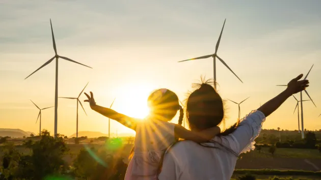 family looking at wind turbine at sunset