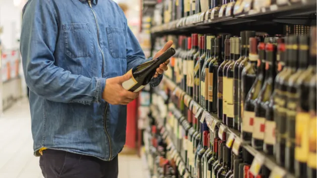 Person buying a bottle of wine at a supermarket 