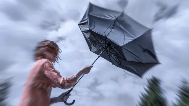 person struggling with an umbrella in the wind and rain