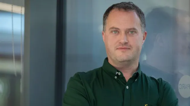 Man leaning against glass door with arms crossed 