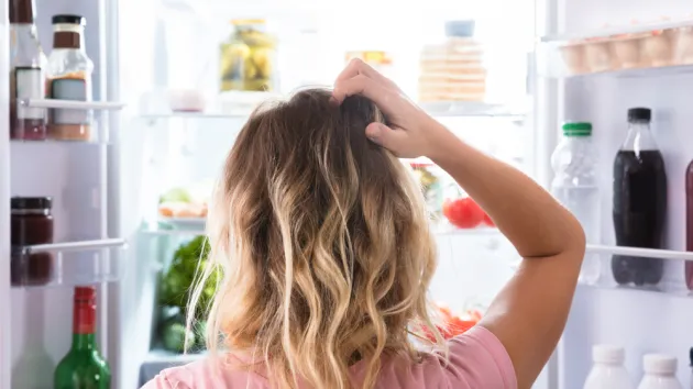 person looking puzzled at fridge contents