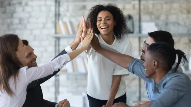 successful businesswoman with business people giving high five, celebrating win.