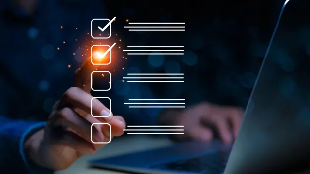 businessman checking mark on checklist on the check boxes with a red marker on dark background.
