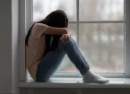 scared young person sitting on a windowsill