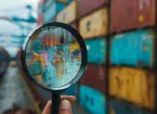 Shipping containers and map of the world viewed through a magnifying glass 