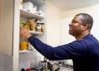 Person looking in a kitchen cupboard at food products 