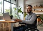 Wheelchair user working in an office talking to a colleague