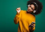 person wearing a yellow sweater, listening to music through headphones 