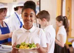 schoolgirl holding a plate of food in canteen 