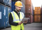 person using a digital device checking shipping containers 
