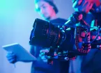 Close-up of operator using professional camera during shooting with director controlling the process