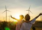 family looking at wind turbine at sunset