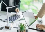 Colleagues discussing climate change, model wind turbines on the desk. 