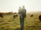 farmer and daughter in a field of cows 