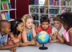 schoolchildren looking at a globe, pointing out different countries 