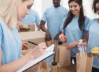 Group of volunteers working with donate food, team leader checking list in clipboard
