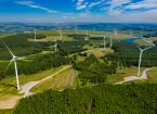 Aerial drone view of turbines at a large onshore windfarm on a green hillside (Pen y Cymoedd, Wales)