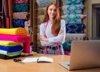 Red haired woman in cotton shirt stand in her dressmaking atelier studio