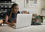  female leather worker using a laptop at a workbench