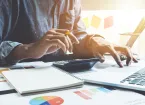 Close up of businessman or accountant hand holding pencil working on calculator to calculate financial data report, accountancy document and laptop computer at office,