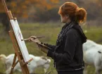 Woman painting - outdoors in a field of cows